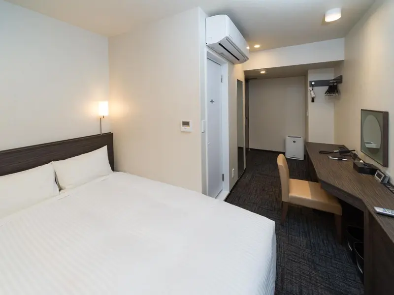 Une chambre d'hôtel lumineuse avec un grand lit et un bureau.
