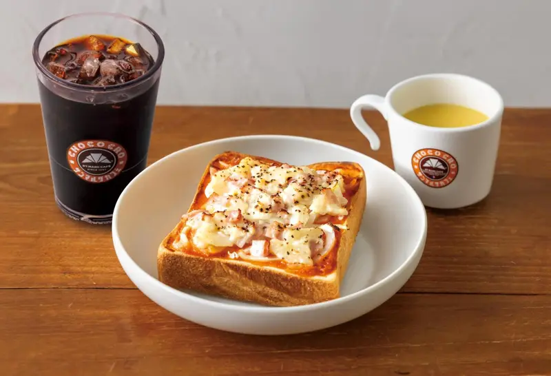 Une tartine gratinée et une boisson glacée sont présentées sur une table en bois.