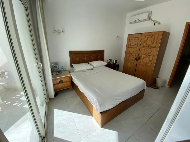 Une chambre lumineuse avec un lit double et un meuble de rangement en bois.