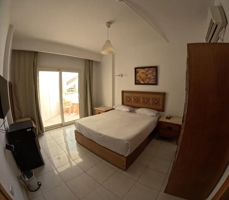 Une chambre lumineuse avec un grand lit et un accès à une terrasse.