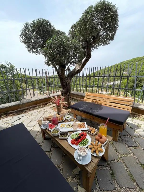 Une table dressée avec des plats et des boissons sur une terrasse pavée.