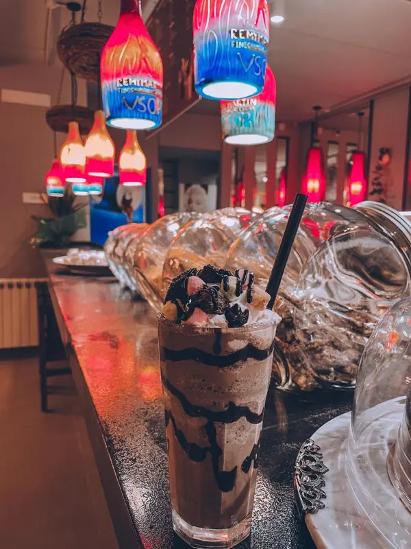 Un verre de boisson glacée décoré est posé sur un comptoir éclairé.
