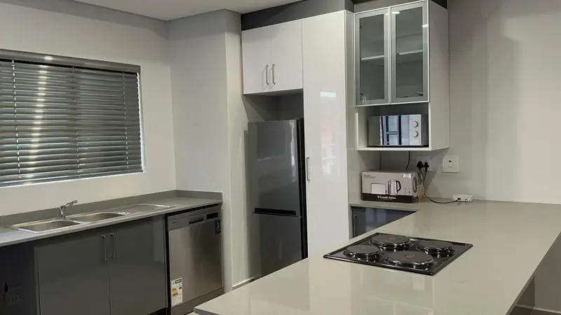 Une cuisine moderne avec des meubles gris et blancs et des appareils en acier inoxydable.