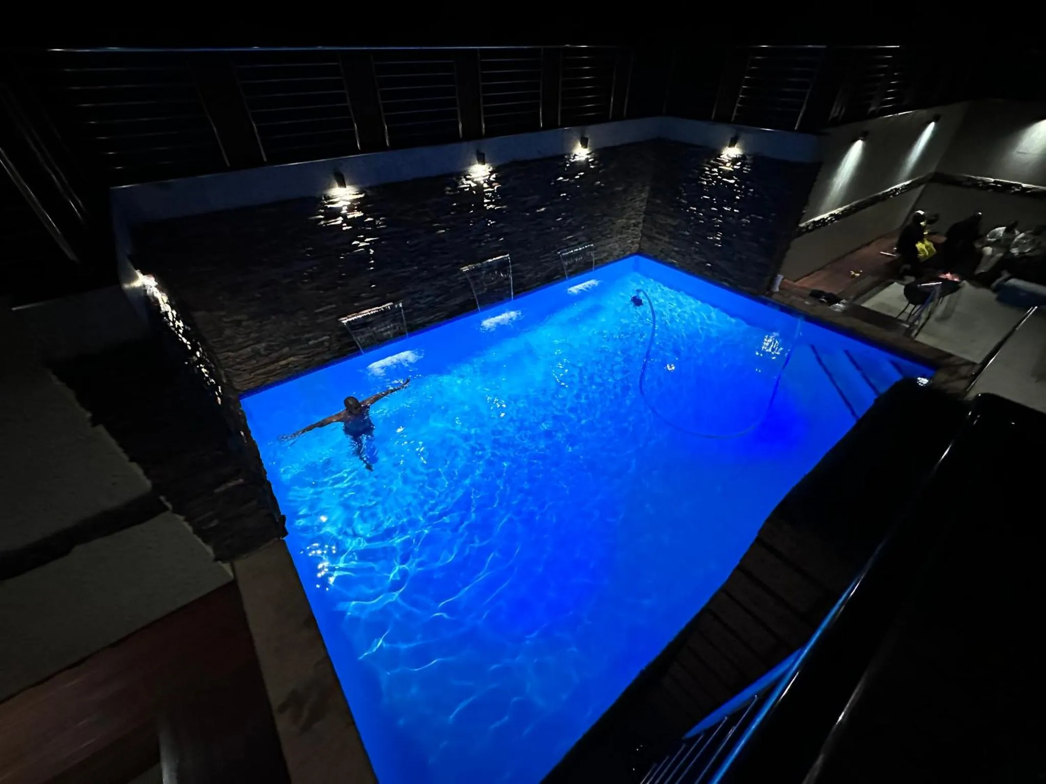 Une piscine illuminée la nuit avec une personne nageant à l'intérieur.