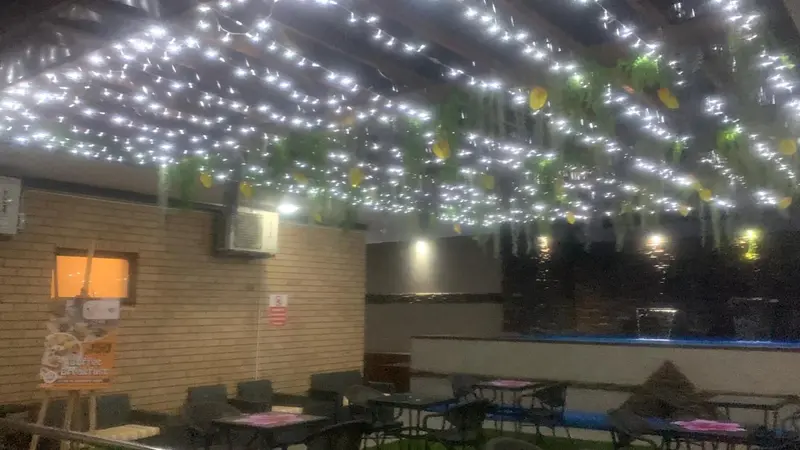 Terrasse illuminée avec tables et chaises.