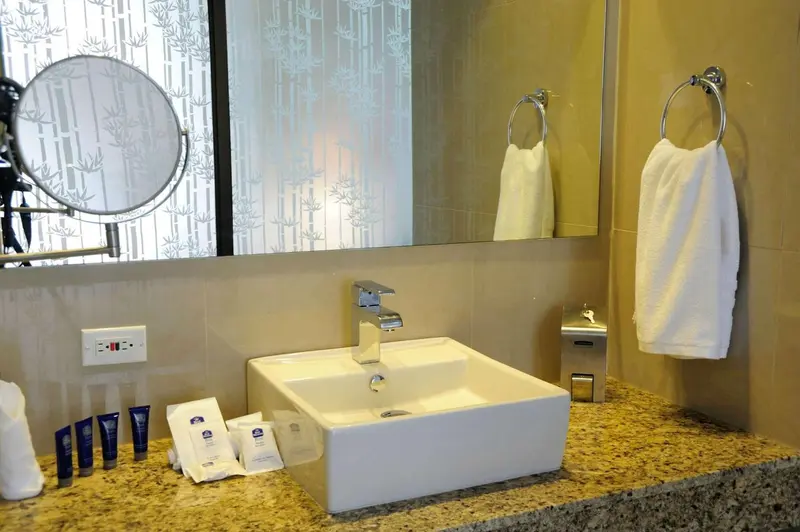 Un lavabo blanc avec des articles de toilette sur un comptoir marbré.