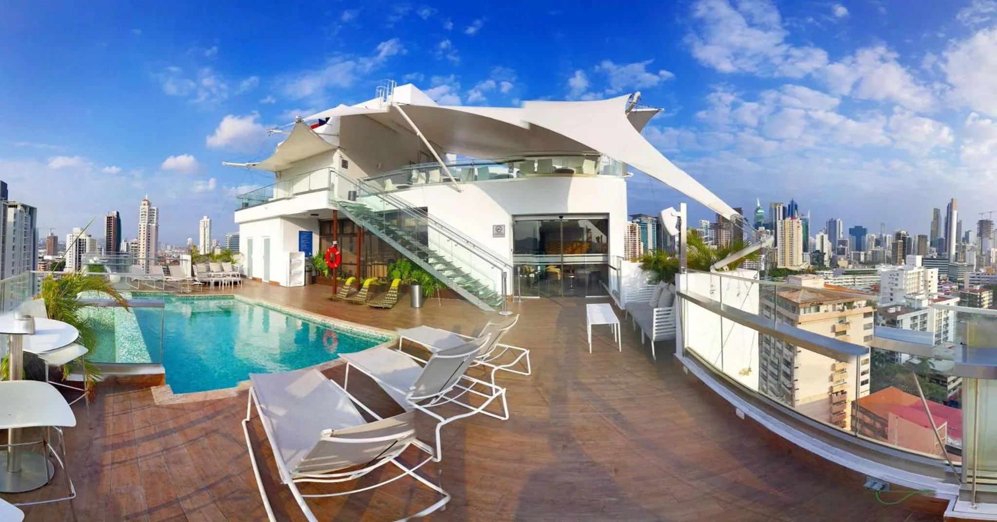 Terrasse sur toit avec piscine et mobilier de détente offrant une vue sur la ville.