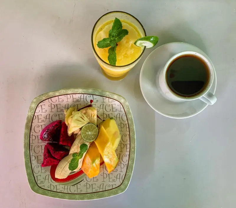 Assiette de fruits frais et boisson servie sur une table blanche.