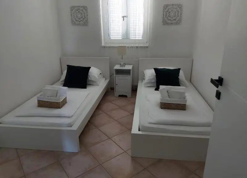 Une chambre lumineuse avec deux lits simples et une décoration sobre.