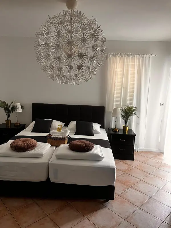 Une chambre avec deux lits simples et un grand lustre décoratif.