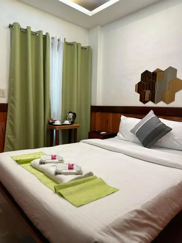 Une chambre lumineuse avec un lit recouvert de draps blancs et de coussins.