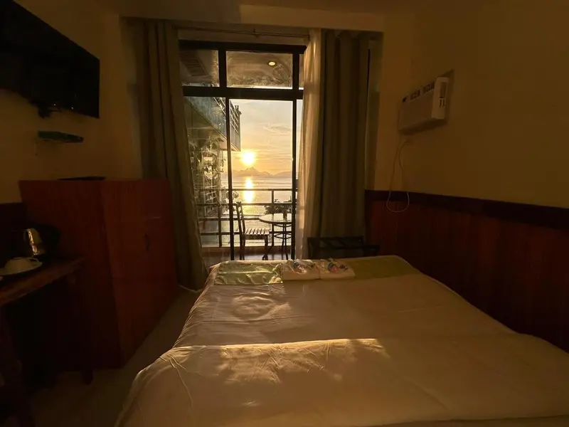 Une chambre lumineuse donne sur une vue dégagée sur la mer au coucher du soleil.