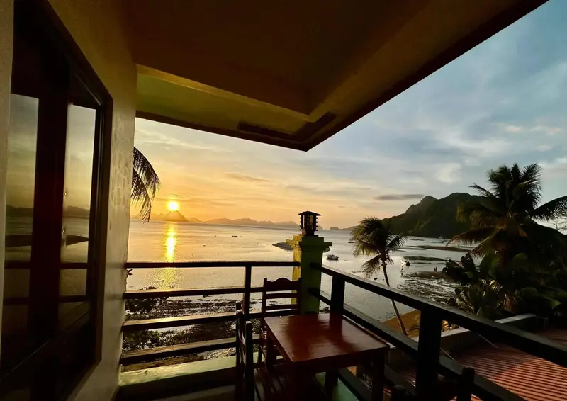 Vue sur un coucher de soleil depuis une terrasse avec mobilier.
