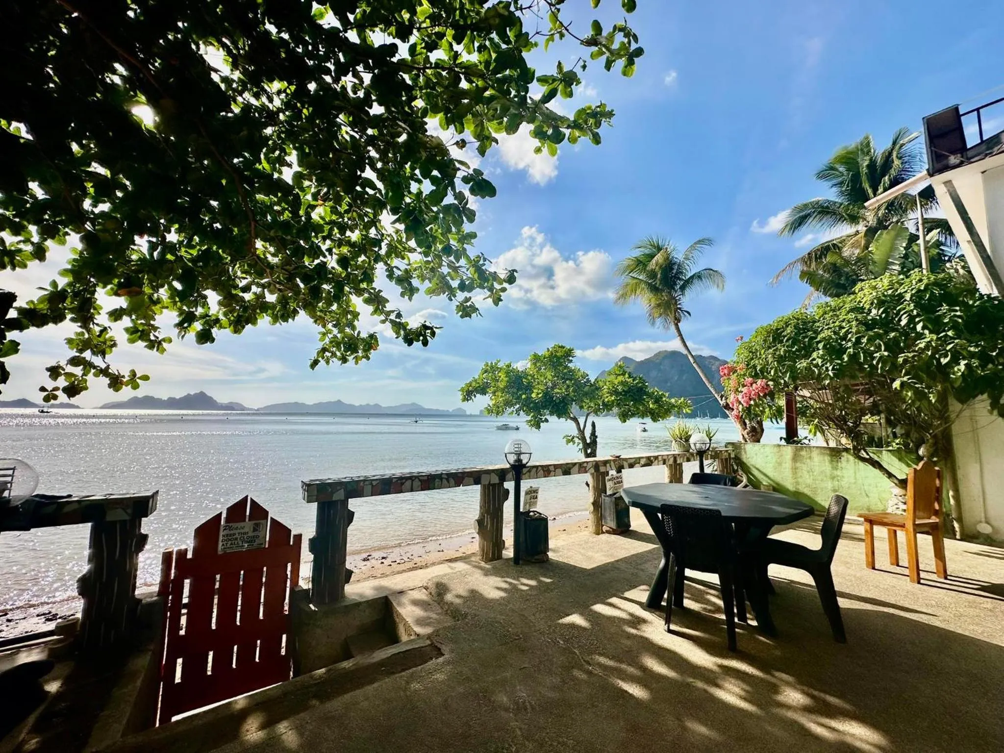 Terrasse ombragée avec tables et chaises donnant sur la mer.