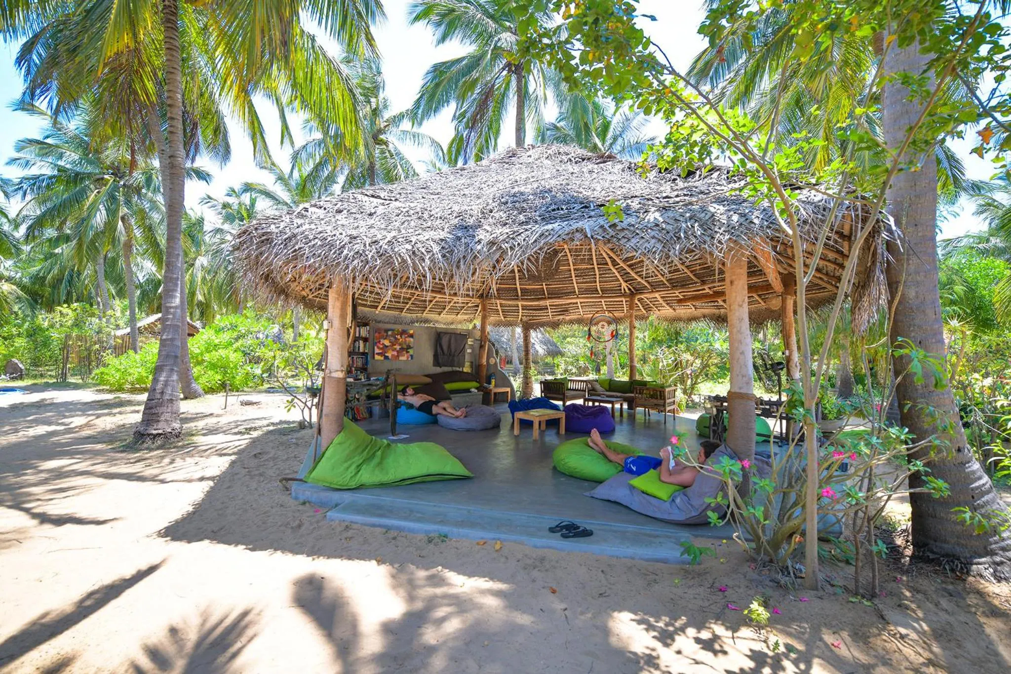 Espace de détente ombragé sur une plage de sable fin.