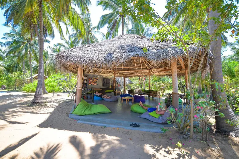 Espace de détente ombragé sur une plage de sable fin.