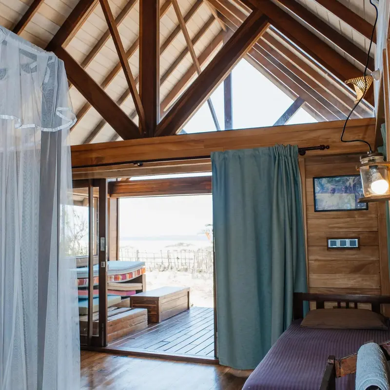 Une chambre lumineuse s'ouvre sur une terrasse en bois.