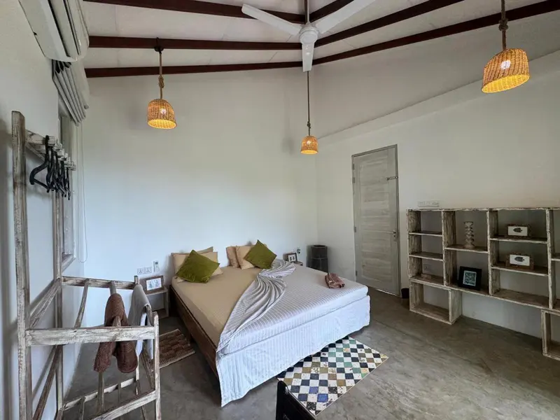 Une chambre lumineuse avec un grand lit et des luminaires en rotin.