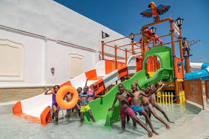 Enfants s'amusant sur des toboggans aquatiques dans une zone de jeux extérieure.