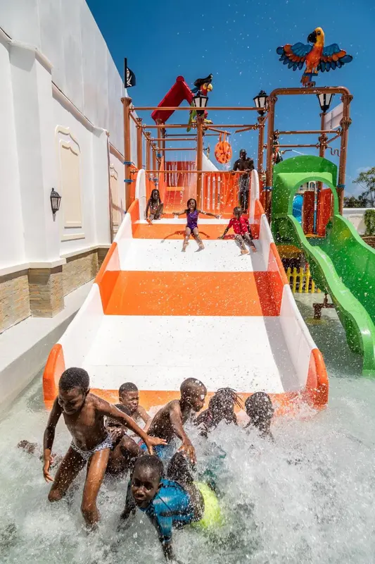 Des enfants s'amusent dans une structure aquatique avec toboggans et jeux d'eau.