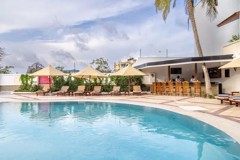 Une piscine turquoise bordée de transats et d'un bar extérieur.