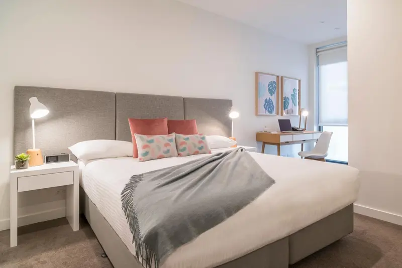 Une chambre lumineuse avec un grand lit et des coussins décoratifs.