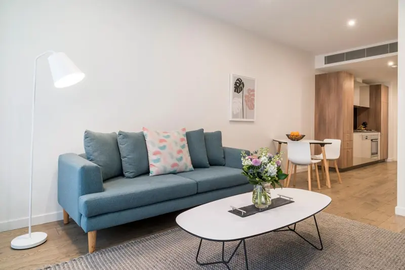 Un salon lumineux avec un canapé bleu-gris et une table basse.
