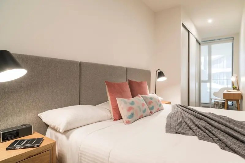 Une chambre lumineuse avec un grand lit et des oreillers décoratifs.
