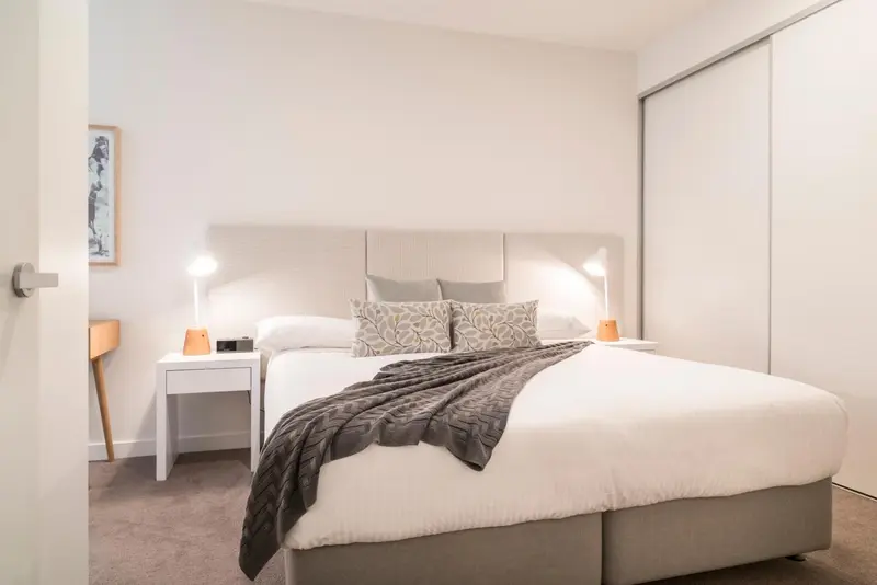 Une chambre lumineuse avec un grand lit recouvert d'une couverture et d'oreillers.