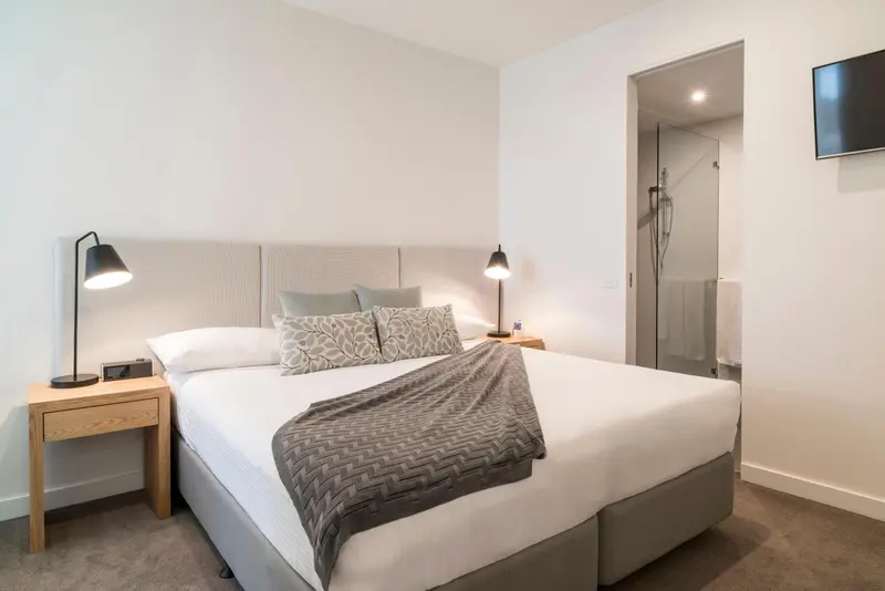 Une chambre lumineuse avec un grand lit et une salle de bain attenante.