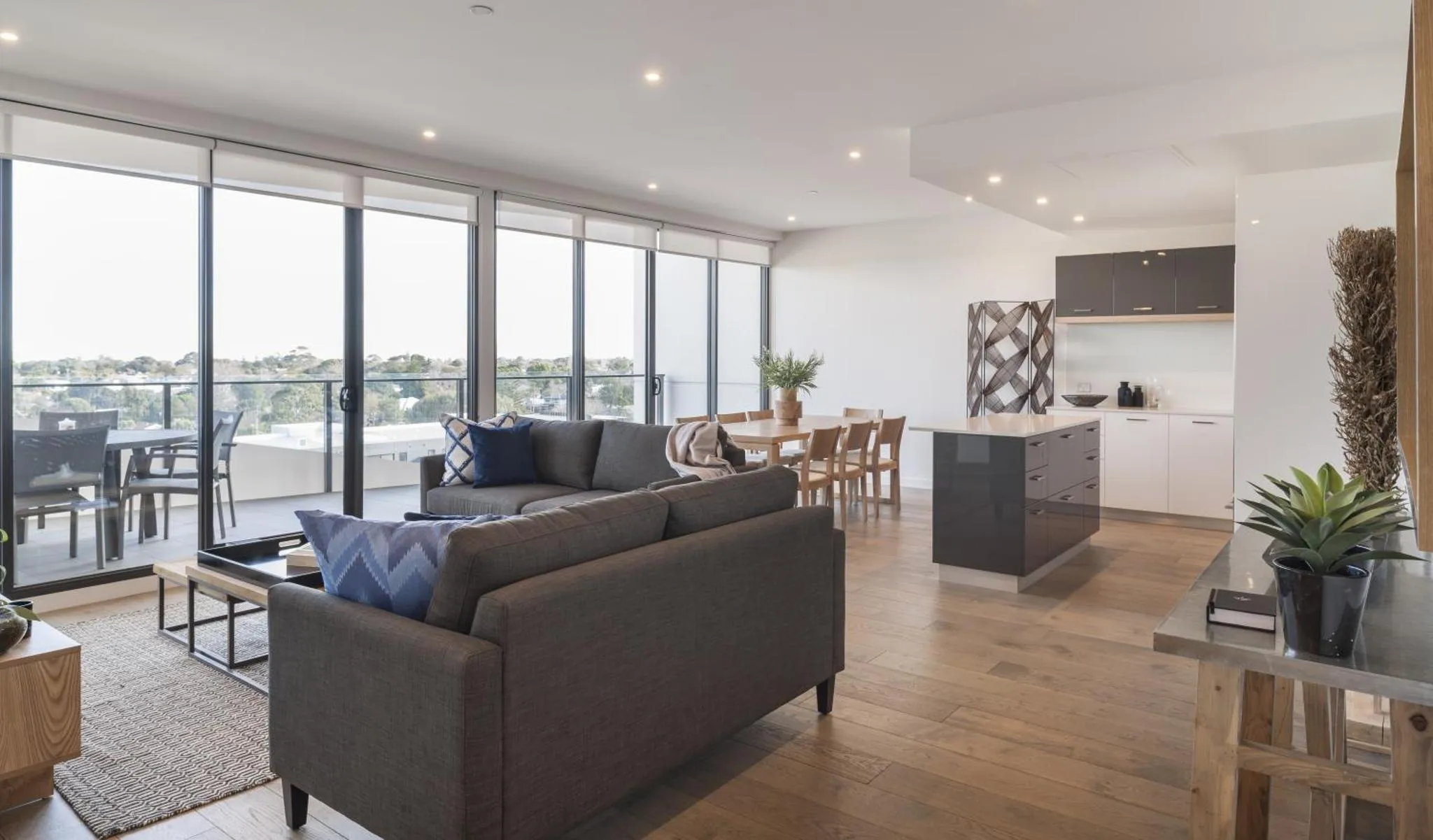 Un espace de vie lumineux avec un coin salon et une cuisine ouverte donnant sur une terrasse.