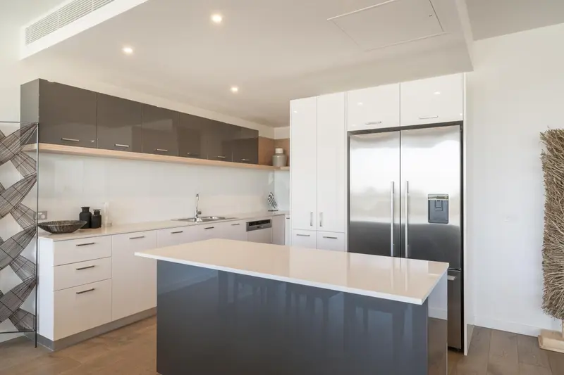 Cuisine moderne avec îlot central et électroménager en inox.