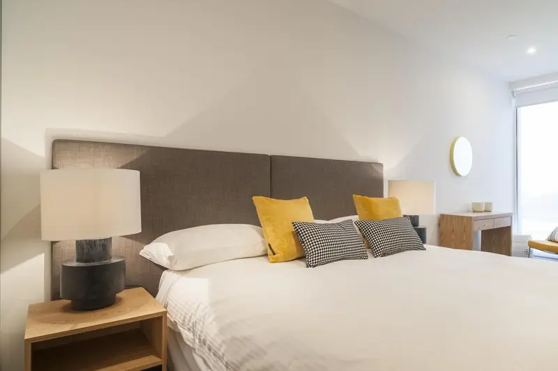 Un lit double avec des oreillers et des lampes de chevet dans une chambre lumineuse.