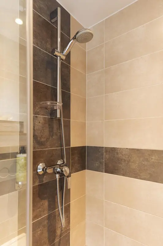 Douche à l'italienne avec pommeau chromé et parois vitrées.
