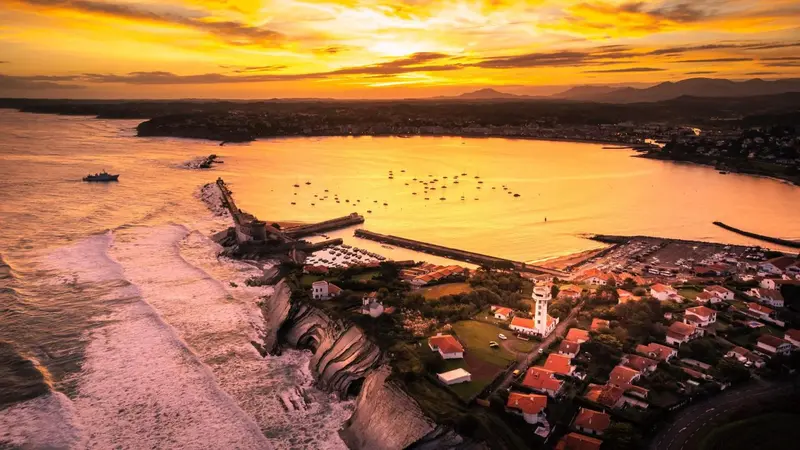 Vue aérienne d'une côte rocheuse baignée par les rayons du soleil couchant.