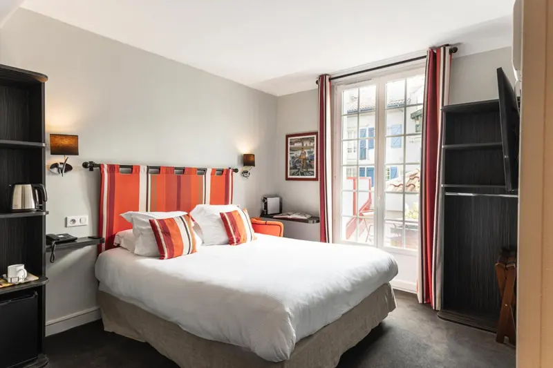Une chambre lumineuse avec un lit double et un accès à un balcon.