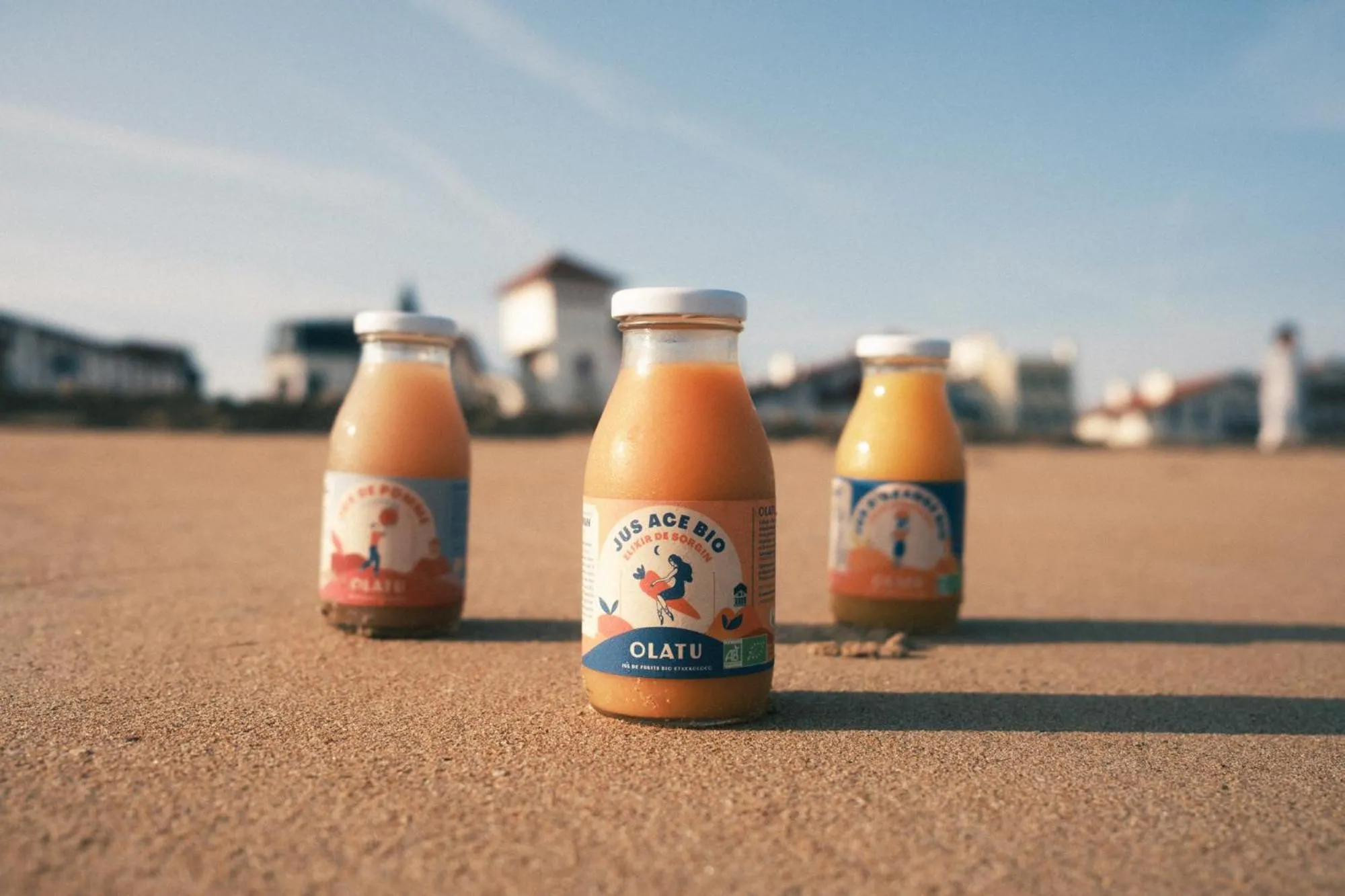 Bouteilles de jus d'orange sur une plage de sable.
