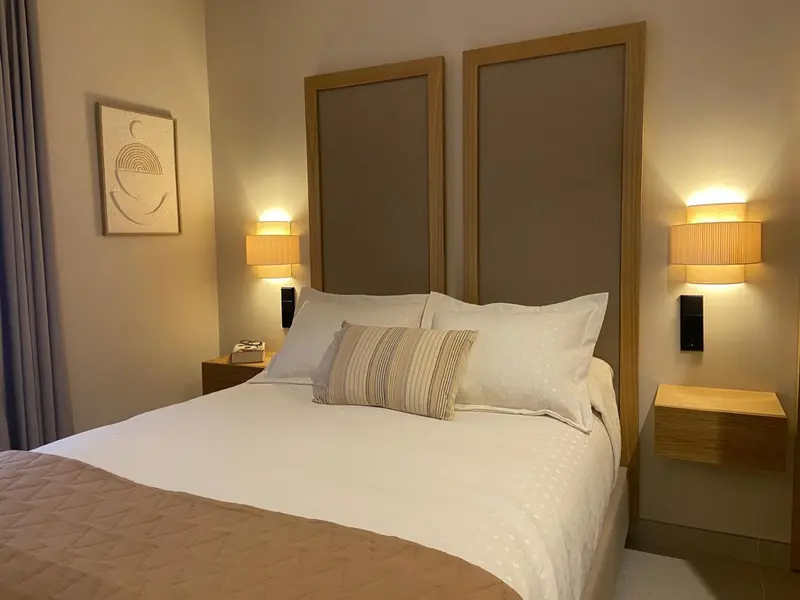 Une chambre lumineuse avec un grand lit recouvert d'une courtepointe et de coussins.
