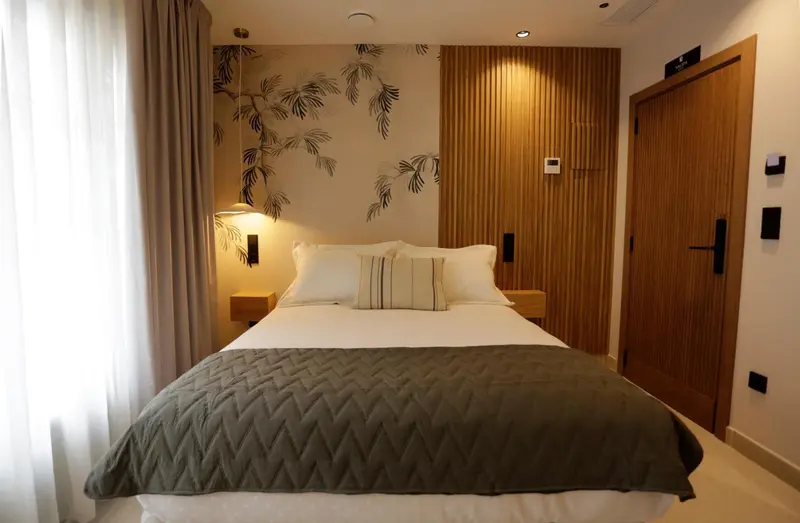 Une chambre lumineuse avec un grand lit recouvert d'une couette et de coussins.