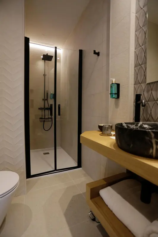 Une salle de bain moderne avec douche à l'italienne et vasque sombre.
