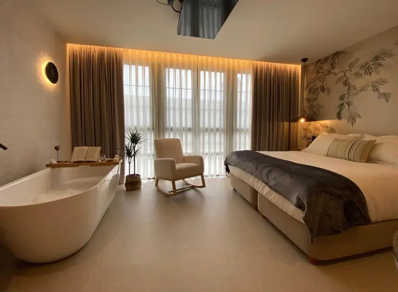 Une chambre lumineuse avec un grand lit et une baignoire.