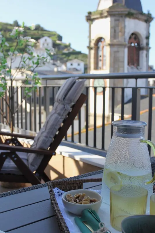 Une table avec une carafe et des collations sur une terrasse ensoleillée.