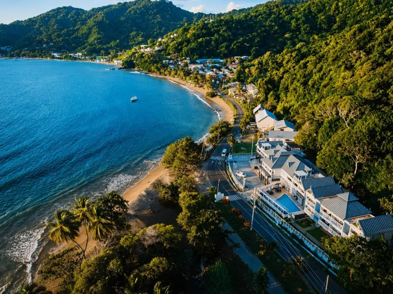 Vue aérienne d'une plage bordée de végétation et d'un complexe hôtelier.