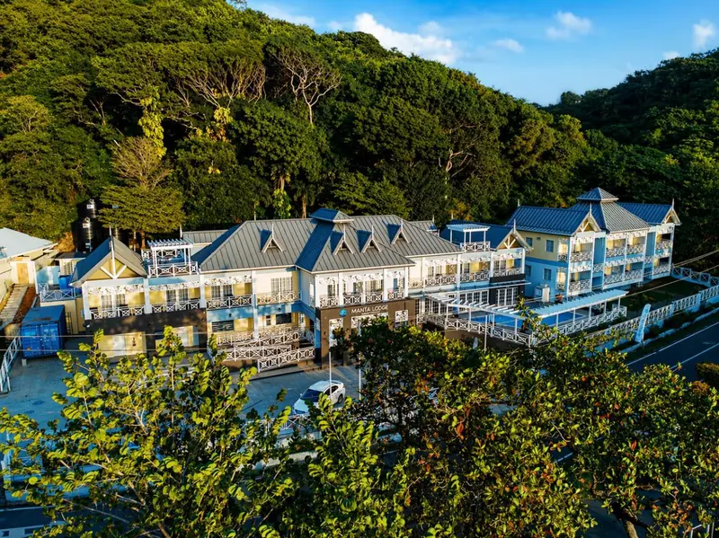 Vue aérienne d'un bâtiment blanc à plusieurs niveaux entouré de végétation luxuriante.
