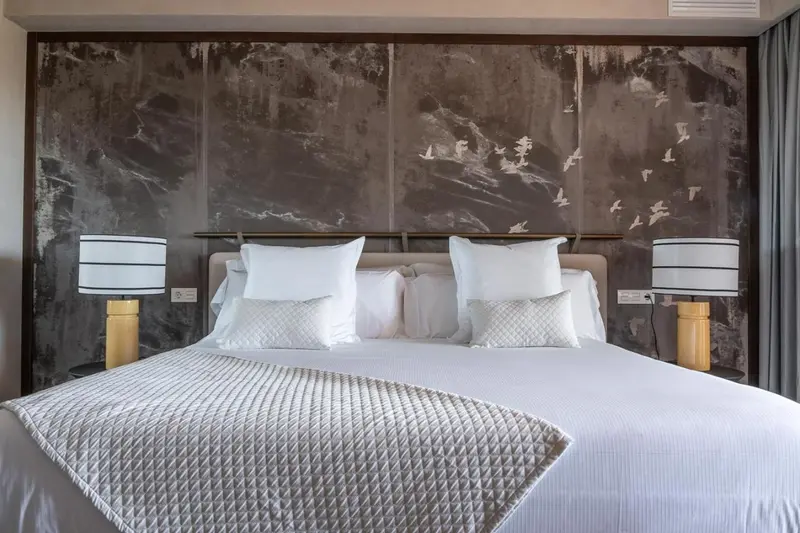 Un lit double est dispose dans une chambre avec une decoration murale abstraite.