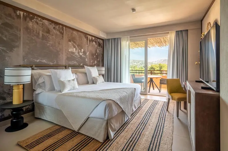 Une chambre lumineuse avec un grand lit et un accès à une terrasse.