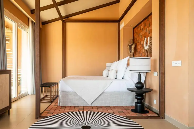 Un lit avec une moustiquaire dans une chambre aux murs ocre.