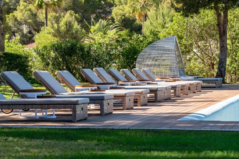 Transats alignés sur une terrasse en bois près d'une piscine.