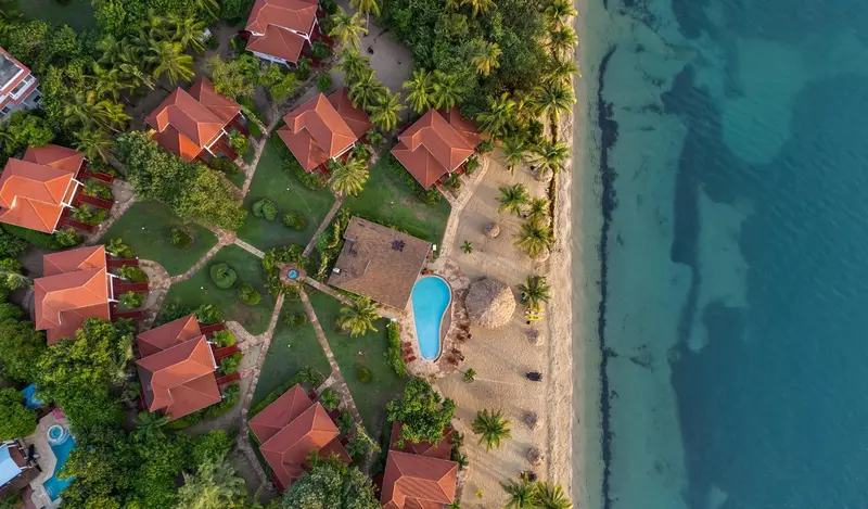 Vue aérienne d'un complexe hôtelier tropical avec piscine et plage.