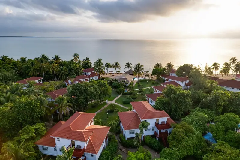 Vue aérienne d'un complexe hôtelier tropical avec des bâtiments aux toits rouges et une végétation luxuriante.